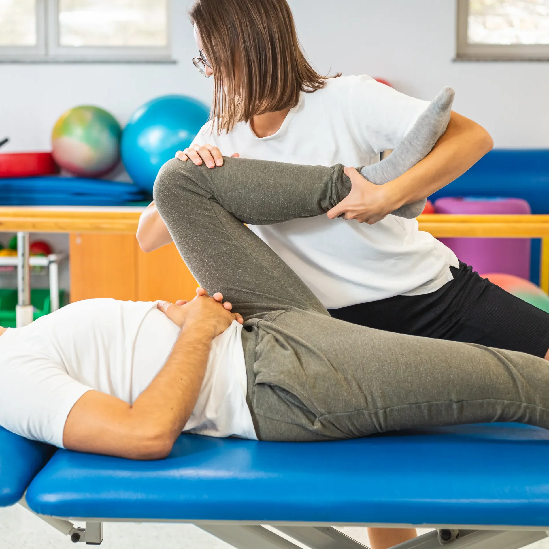 a physiotherapist stretching her patient's leg with a manual therapy technique to help alleviate their sciatica pain
